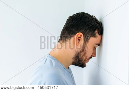 Side View Of An Unhappy Man Resting Head Against Office Wall. Worker Banging His Head Against The Wa