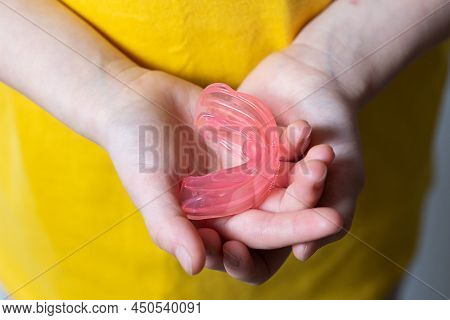 Cute Girl With Blond Hair Is Holding A Pink Dental Myofunctional Trainer
