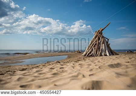 Stacked Light Trees And Branches By The Sea, Like A Wigwam Or A Bonfire. Natural Landscape In Latvia