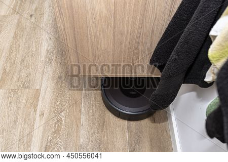 A Modern Robotic Vacuum Cleaner Cleans The Ceramic Tiles In The Bathroom Next To The Wall Mounted Ca
