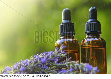 Lavender Oil And Lavender Sprigs On Blurred Green Background.base Cosmetic Oil For Massage And Care 