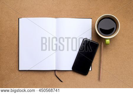 Top View With Blank Notebook,smartphone,pencil And Coffee On Brown Wood Table Background. Fat Lay Of