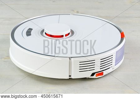 Robot Vacuum Cleaner On The Wooden Floor Cleaning The Room. Smart Cleaning And Washing Technology. A