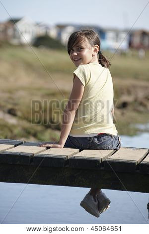 Ragazza seduta sul ponte sorridendo alla telecamera
