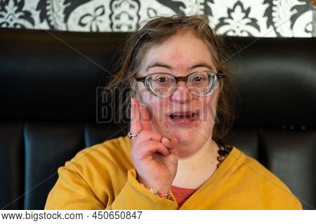 Indoor Portrait Of A 39 Year Old White Woman With The Down Syndrome, Doing The Peace Sign