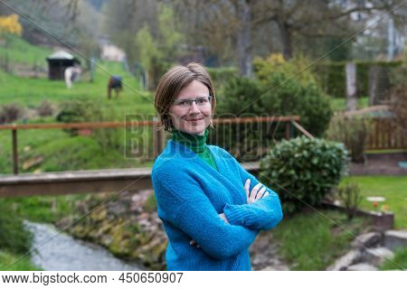 Close Up Portrait Of A Young White Woman With Glasses Wearing A Blue And Green Sweater With A Green 