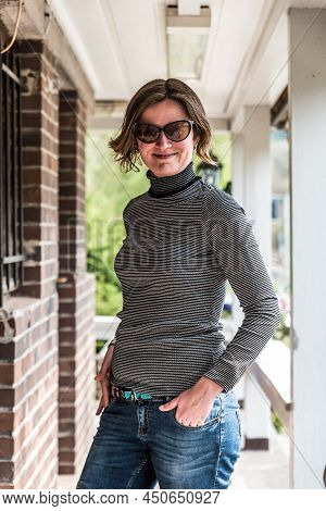 Young Thirty Year Old White Woman In A Relaxed Jeans And Sweater Outfit Posing Near An Abandonned Ca