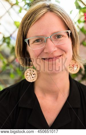 Portrait Of A Thirty Year Old White Caucasian Lady With Glass, Golden Earrings And A Black Dress, Br