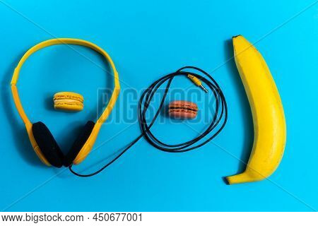 Minimalism Flat Lay Concept, Listens To A Music. Headphones, Banana On Blue Background. Top View