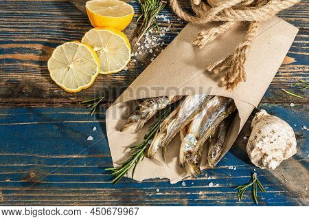 Sun-dried Smelt In A Paper Package. Salted Fish With Marine Decor. Lemon, Fresh Rosemary, Sea Rope