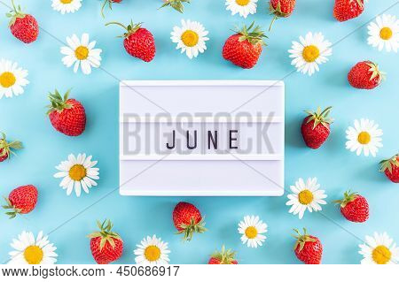 Summer Month June Text On Light Box And Strawberry, Chamomile Flowers On Blue Background. Top View F
