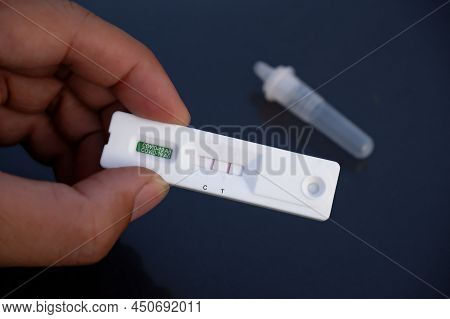 Human Hand Displays A Covid-19 Positive Result Cassette From A Rapid Antigen Test Kit (atk)