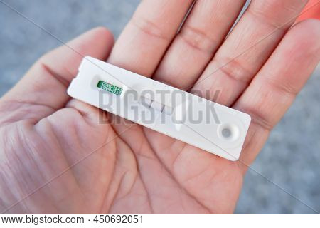 Human Hand Displays A Covid-19 Positive Result Cassette From A Rapid Antigen Test Kit (atk)
