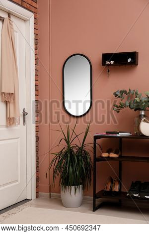 Hallway Interior With Green Plants And Wooden Hanger For Keys On Pale Pink Wall