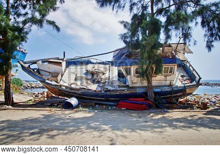 Dondra Port, Sri Lanka. Abandoned Fishing Boat On The Shore. Dirty Harbor And Old Ships.