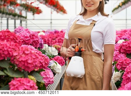 Close Up Of Young Woman In White Shirt And Special Beige Uniform Holding Polivizator Among Beautiful