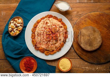 Couscous Masfouf With Dried Fruits In A Plate On A Wooden Table Next To Saffron, And Couscous Grits 
