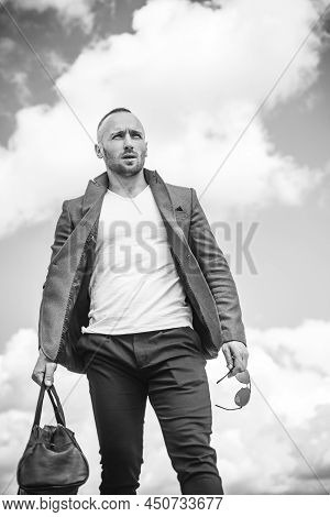 Confident Attractive Man Waiting For His Transport Wearing A White T-shirt, Brown Jacket, And Comfor