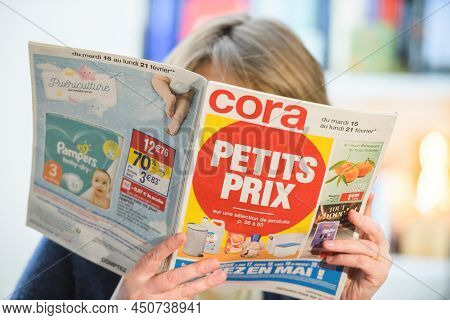 Paris, France - Feb 23, 2022: Woman Reading Cora Hypermarket Special Offer Leaflet Flyer Choosing Be