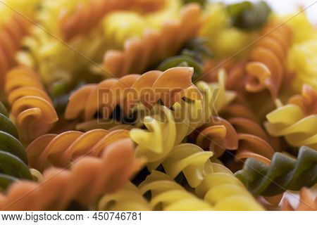 Three Colors Pasta Made From Durum Wheat. Pasta Fusilli Tricolor Background. Abstract Texture Of Col