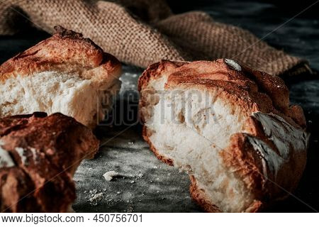 closeup of a round kamut wheat bread broken in some pieces on a mottled dark gray fabric surface
