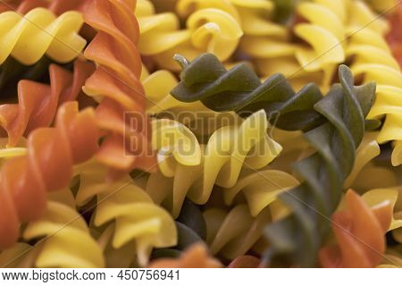 Three Colors Pasta Made From Durum Wheat. Pasta Fusilli Tricolor Background. Abstract Texture Of Col
