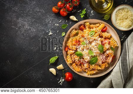 Italian Pasta Alla Arrabiata With Basil And Parmesan Cheese On Dark Table. Fusilli Pasta With Tomato