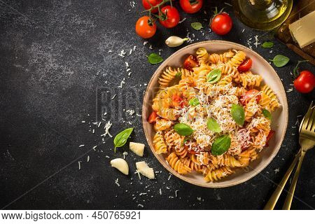 Italian Pasta Alla Arrabiata With Basil And Parmesan On Black Stone Table. Fusilli Pasta With Tomato