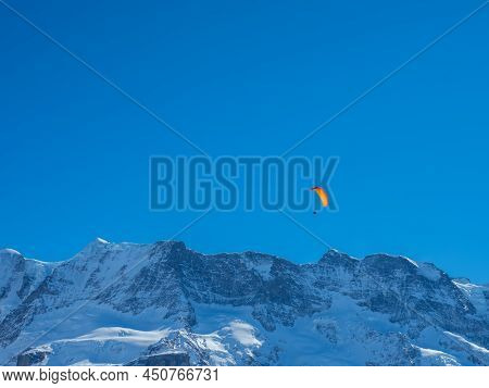 A Paraglider In Front Of A Snow Covered Mountain Ridge In Switzerland