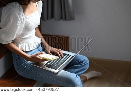 Young Girl Sitting On Sofa And Using Digital Tablet Doing Homework Online During Extra Curricular Cl