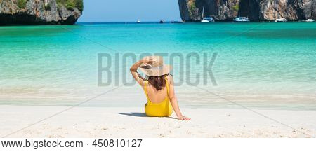 Woman Tourist In Yellow Swimsuit And Hat, Happy Traveller Sunbathing At Maya Bay Beach On Phi Phi Is