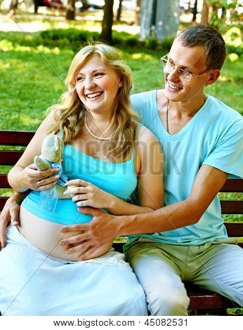 Donna incinta, tenendo il fiore con l'uomo all'aperto nel parco.