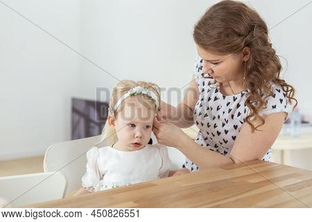 Mother Helps To Put On Cochlear Implant For Her Deaf Little Daughter. Hearing Aid And Deafness Conce