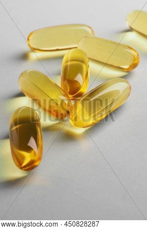 Fish Oil. Yellow Softgels Or Capsules Lie On White Or Light Gray Surface. Vertical Illustration Abou