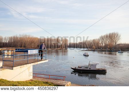 Kovin, Serbia - February 6, 2022: Old Man Standing And Meditating In Front Of The Port Of Kovin, On 