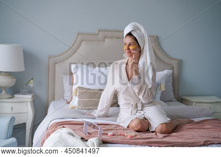 Woman With Towel On Her Head Doing Beauty Routine With Gua Sha Quartz Roller At Home. Girl In Bathro