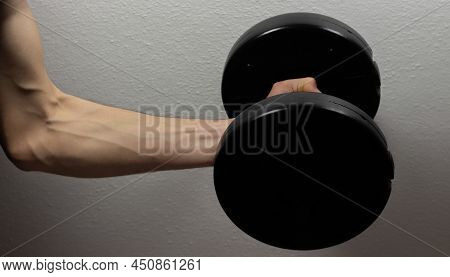 Hand Holding Black Dumbbell, Shadowy Arm Carrying Dumbbell In Gloomy Room