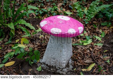 Pink And White Painted Stone Mushroom Seat In Enchanted Woodland Fairy Garden, Surrounded By Mature 