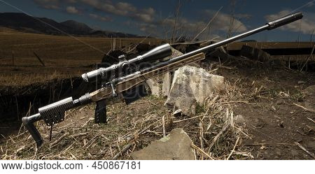 High Powered Rifle In A Field With A Suppressor And Riflescope