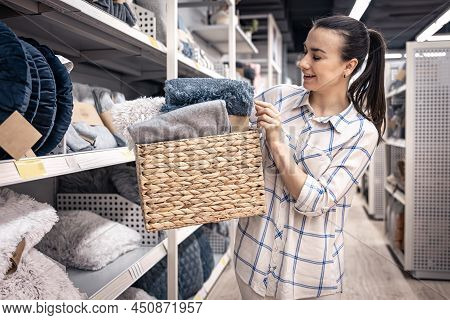A Young Woman With A Wicker Basket Full Of Blankets In A Home Improvement Store.