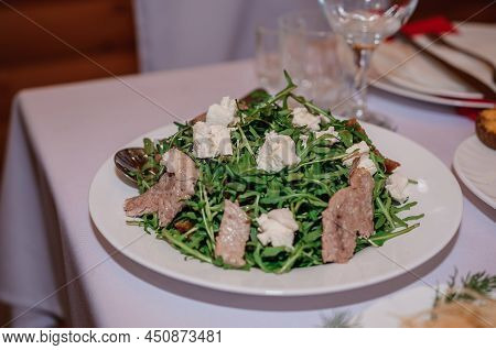 Salad With Arugula, Cheese And Meat On A White Plate