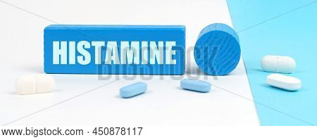 Medical Concept. On A White And Blue Surface Are Pills, A Stethoscope, A Pen And A Wooden Sign With 