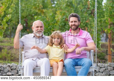 Generations Family. Grandfather With Son And Grandson On A Swing In Spring Garden Outdoors. Active P