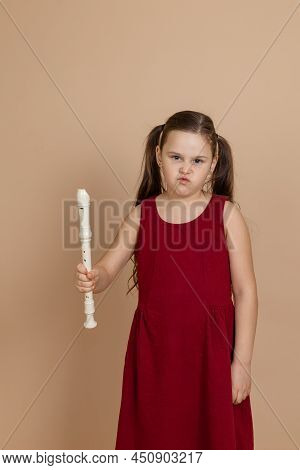 Girl In Red Dress With Displeased Expression Hold Common Flute In Hand, Beige Background. Learning T