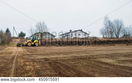 Tractor Levels Field. Backhoe Loader Clearing Construction Site. Bulldozer Prepares Building Ground.
