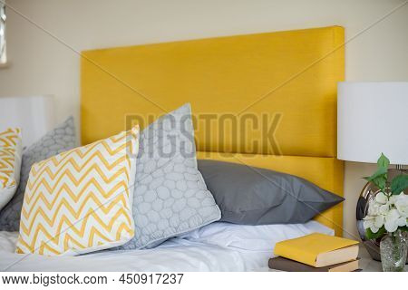 Modern Bedroom Bed Detail With Yellow Fabric Headboard, Pillows, Cushions And Sidetable Drawer With 