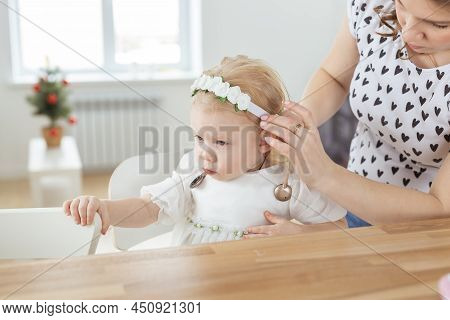 Mother Helps To Put On Cochlear Implant For Her Deaf Little Daughter. Hearing Aid And Deafness Conce
