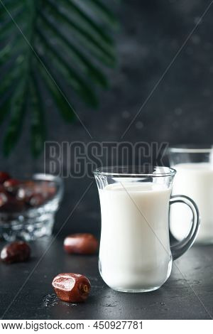 Ramadan Kareem Food And Drinks. Plate Of Dates, Glass Of Milk And Date Palm Branch On Black Backgrou