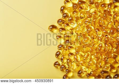 Pile Of Golden Capsules Of Vitamin D3 On A Yellow Background With Free Space