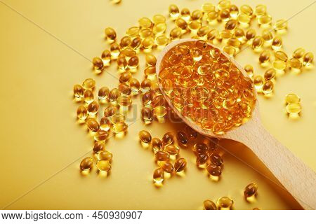 Vitamin D3 In A Wooden Spoon On A Bright Yellow Background